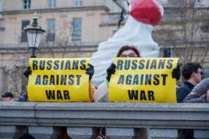 A Russian citizen holds a protest sign opposing the war in Ukraine, symbolizing the risks faced by Russian dissidents seeking asylum in the United States.